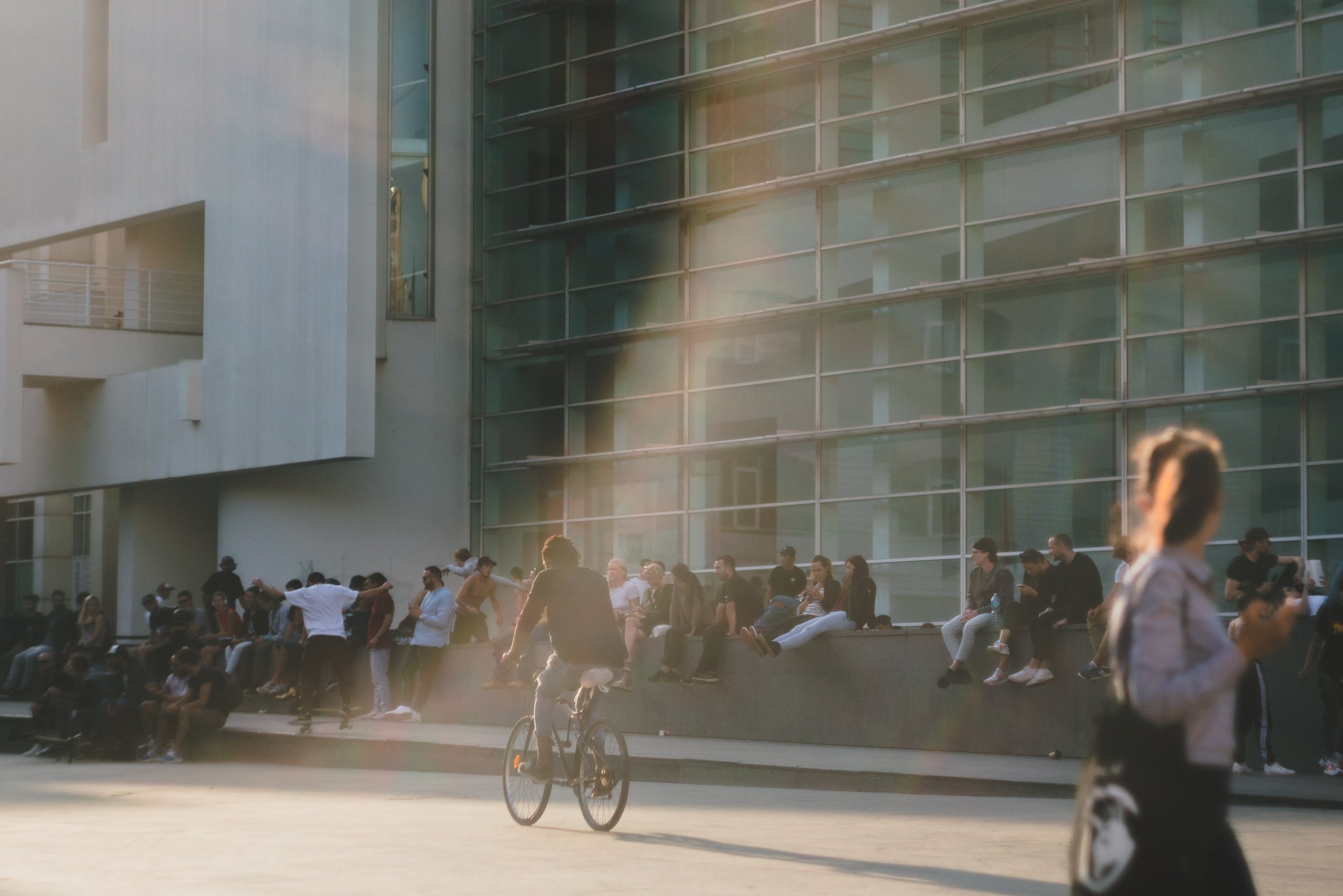 People sitting on a ledge in front of a modern building with a blurred effect